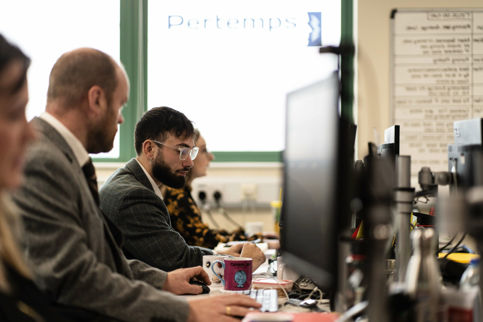 A photo of the pertemps office, with Branden in focus looking at his laptop