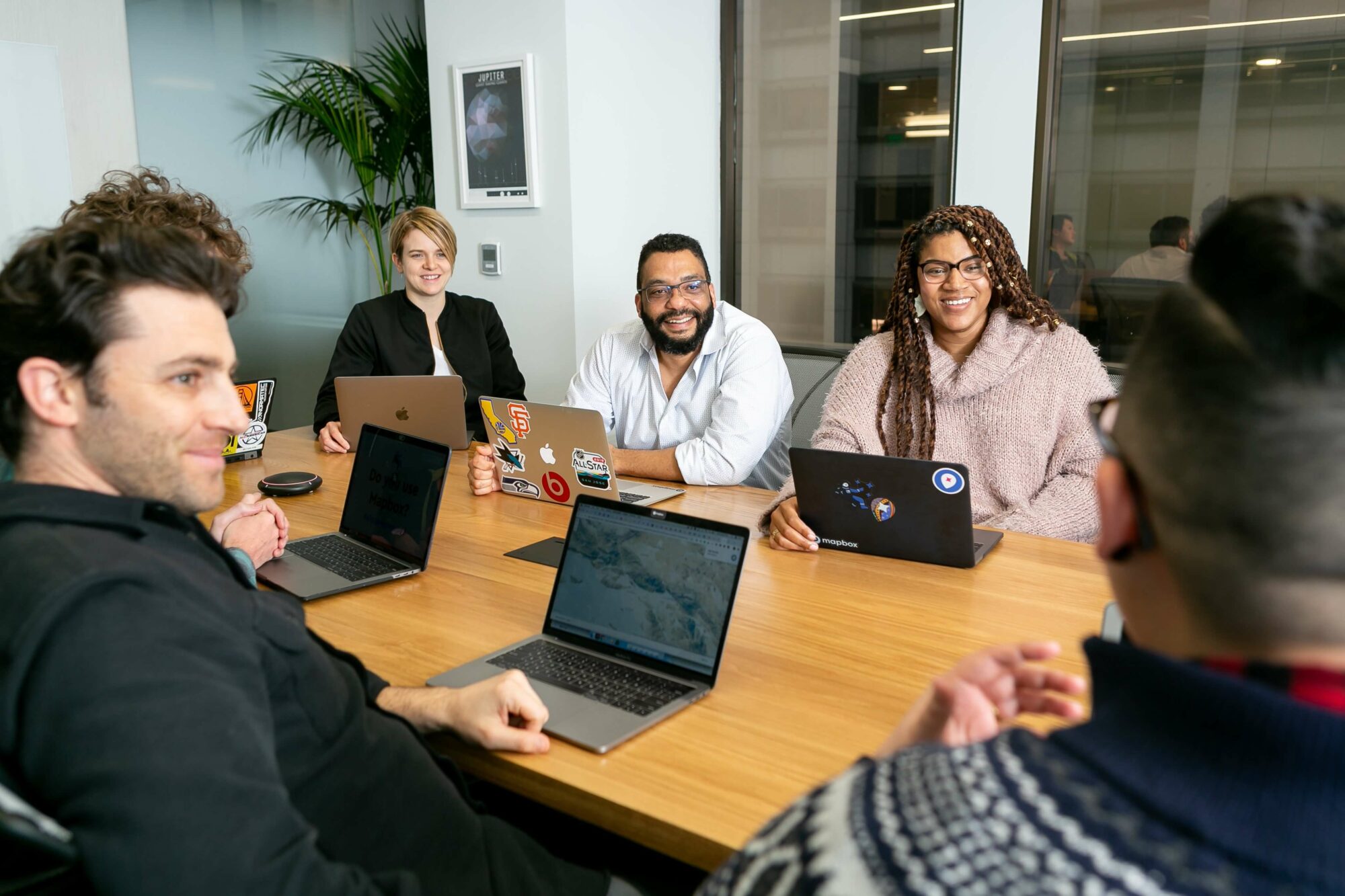 4 people in an office on laptops smiling