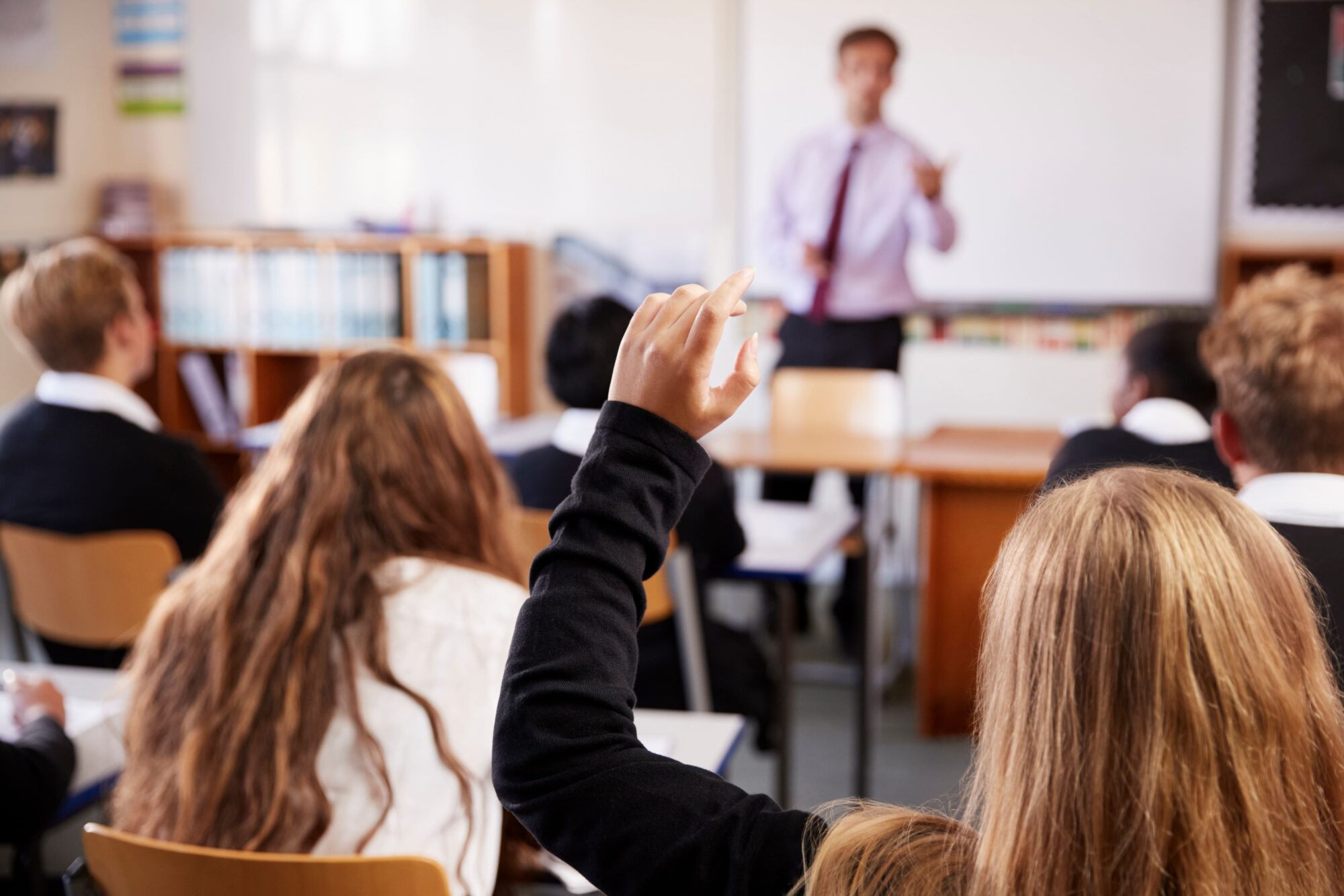a young child's arm raised in the air for the attention of the teacher