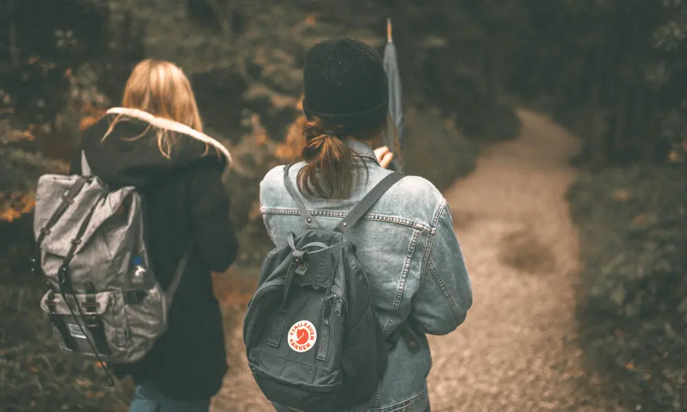 photo of two young women from behind with backpacks on as if on a hike